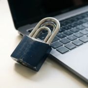 hangslot-laptop-beveiliging-cybersecurity.jpg Combinatieslot op laptoptoetsenbord symboliseert gelaagde digitale beveiliging op modern kantoorbureau.