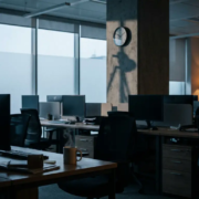 kantoor-stilstand-verlaten-werkplek-crisis.jpg Verlaten kantoor tijdens werkdag met lege stoelen, dampende koffiekop op bureau en één amber lamp in koelblauwe stilte.