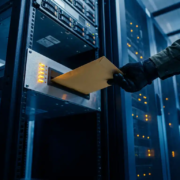 serverbeheer-melding-datacenter-waarschuwing-technicus.jpg Gehandschoende IT-professional plaatst verzegelde envelop in serverzaal alertpaneel met knipperende amber lampjes en rackservers op de achtergrond.