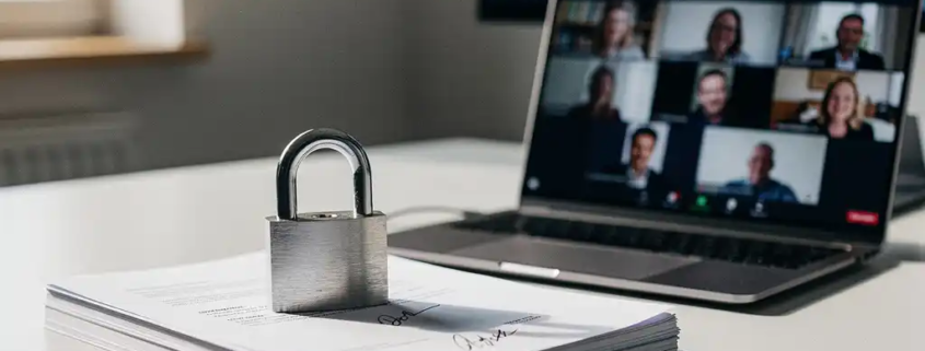 Beveiligd hangslot op stapel ondertekende documenten naast laptop met videovergadering, modern kantoor met noordelijk daglicht.