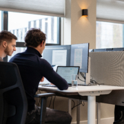 Werknemers werken samen achter een computer scherm