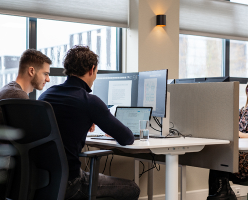 Werknemers werken samen achter een computer scherm