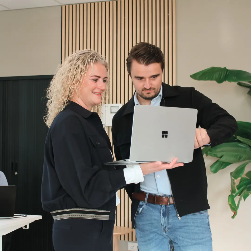 Identity & Access Twee medewerkers van Puur ICT staan samen bij een laptop, terwijl één van hen naar het scherm wijst.