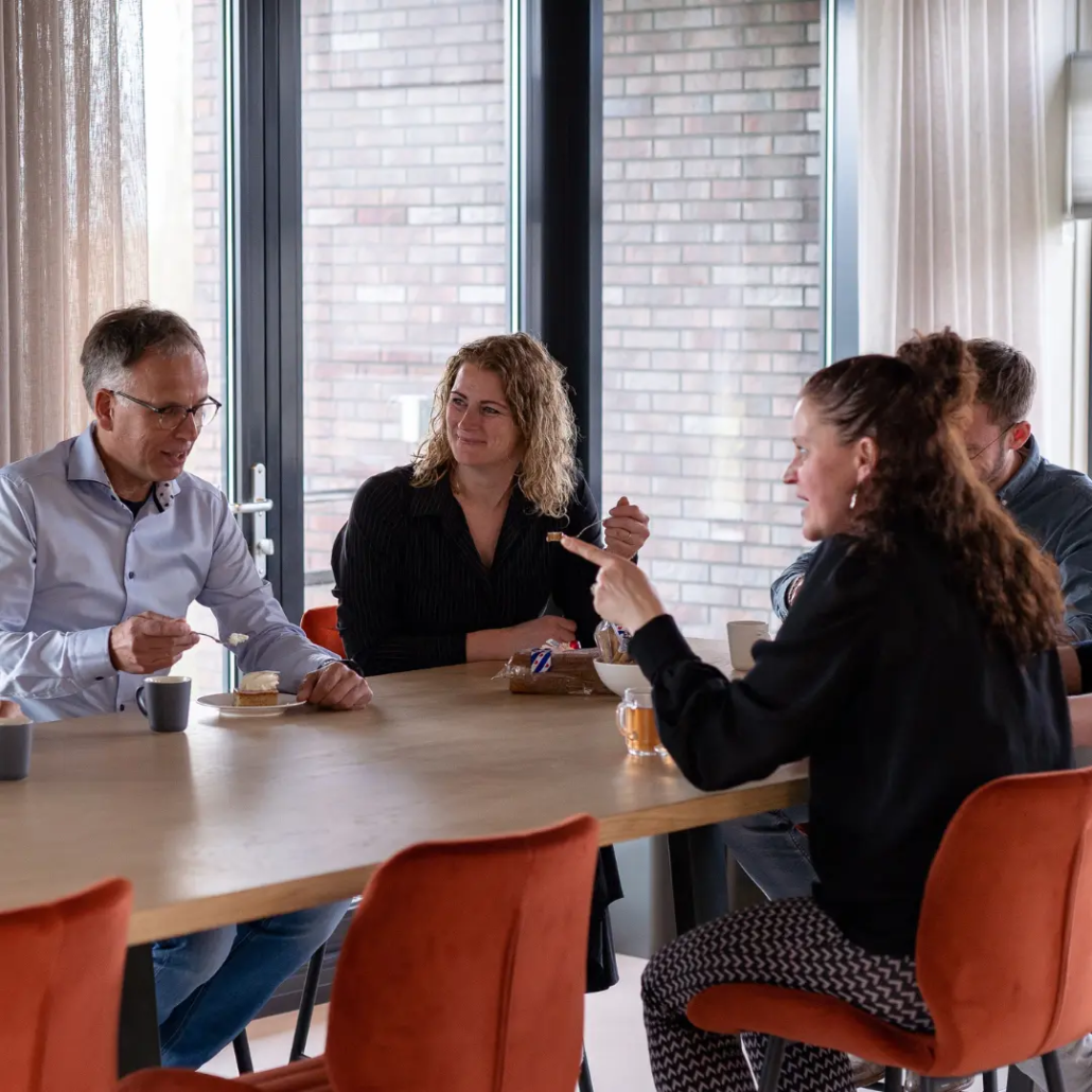 Microsoft 365 trainingen Een groep collega’s van Puur ICT zit samen aan de lunchtafel en is met elkaar in gesprek.