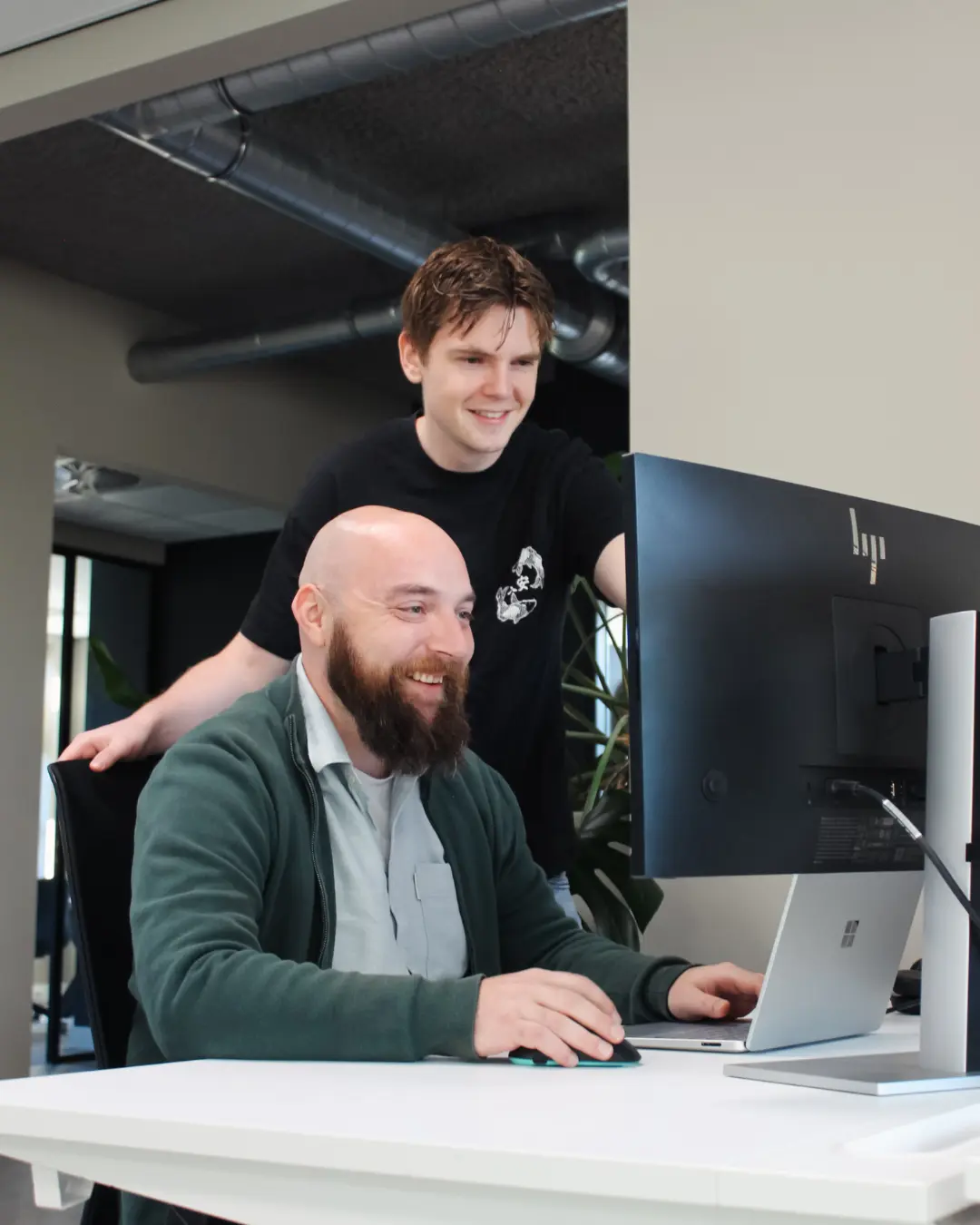 Microsoft Power Platform Twee medewerkers van Puur ICT overleggen op de servicedesk en kijken samen naar het computerscherm.