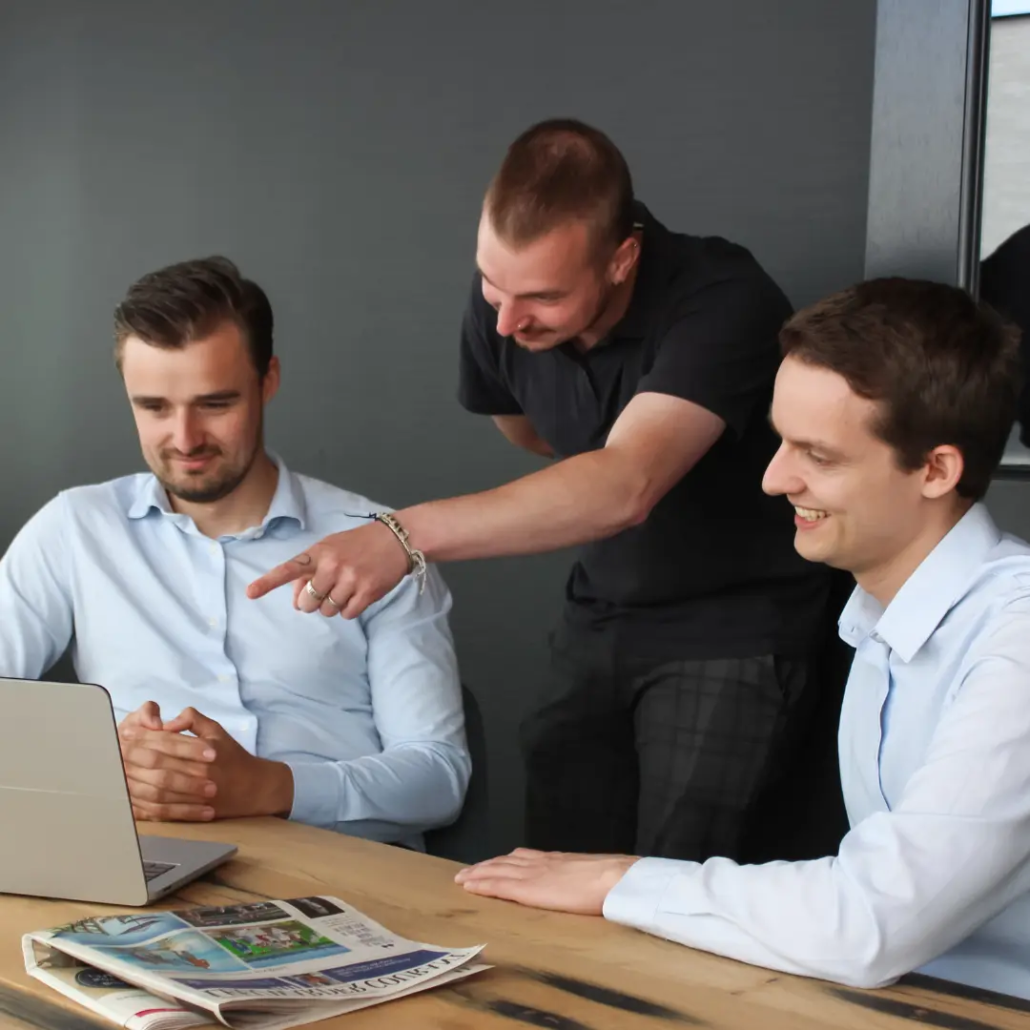 NIS2 & Digitale Weerbaarheid Drie medewerkers van Puur ICT kijken samen naar een laptop, terwijl één van hen naar het scherm wijst.