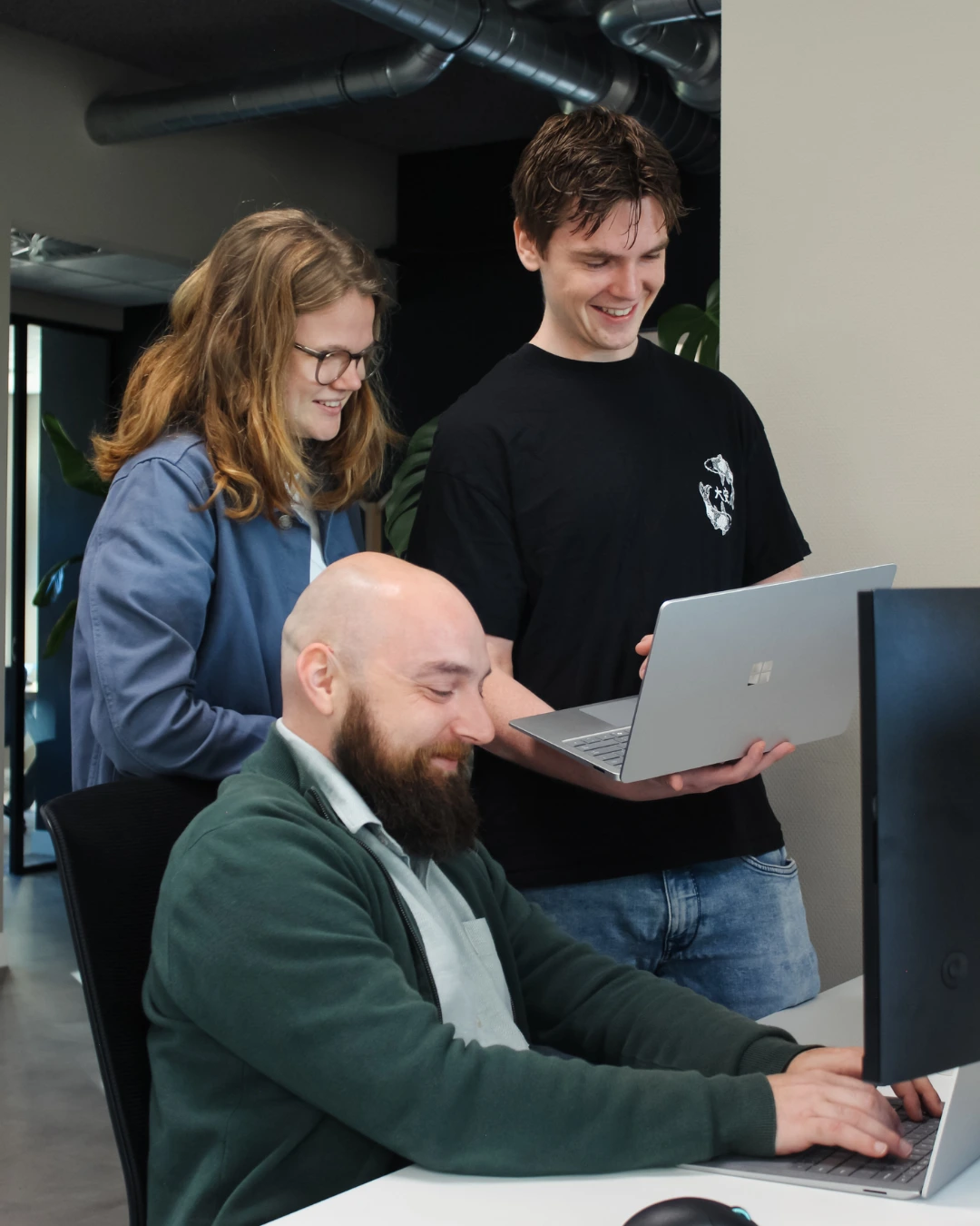 Drie medewerkers van Puur ICT overleggen op de servicedesk en kijken samen naar het computerscherm.