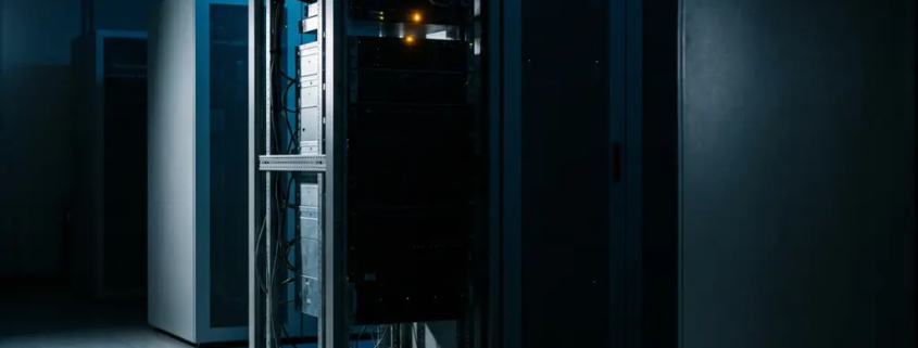 Actieve serverrack met oranje indicatielamp in donker datacenter verlicht door blauw noodlicht.